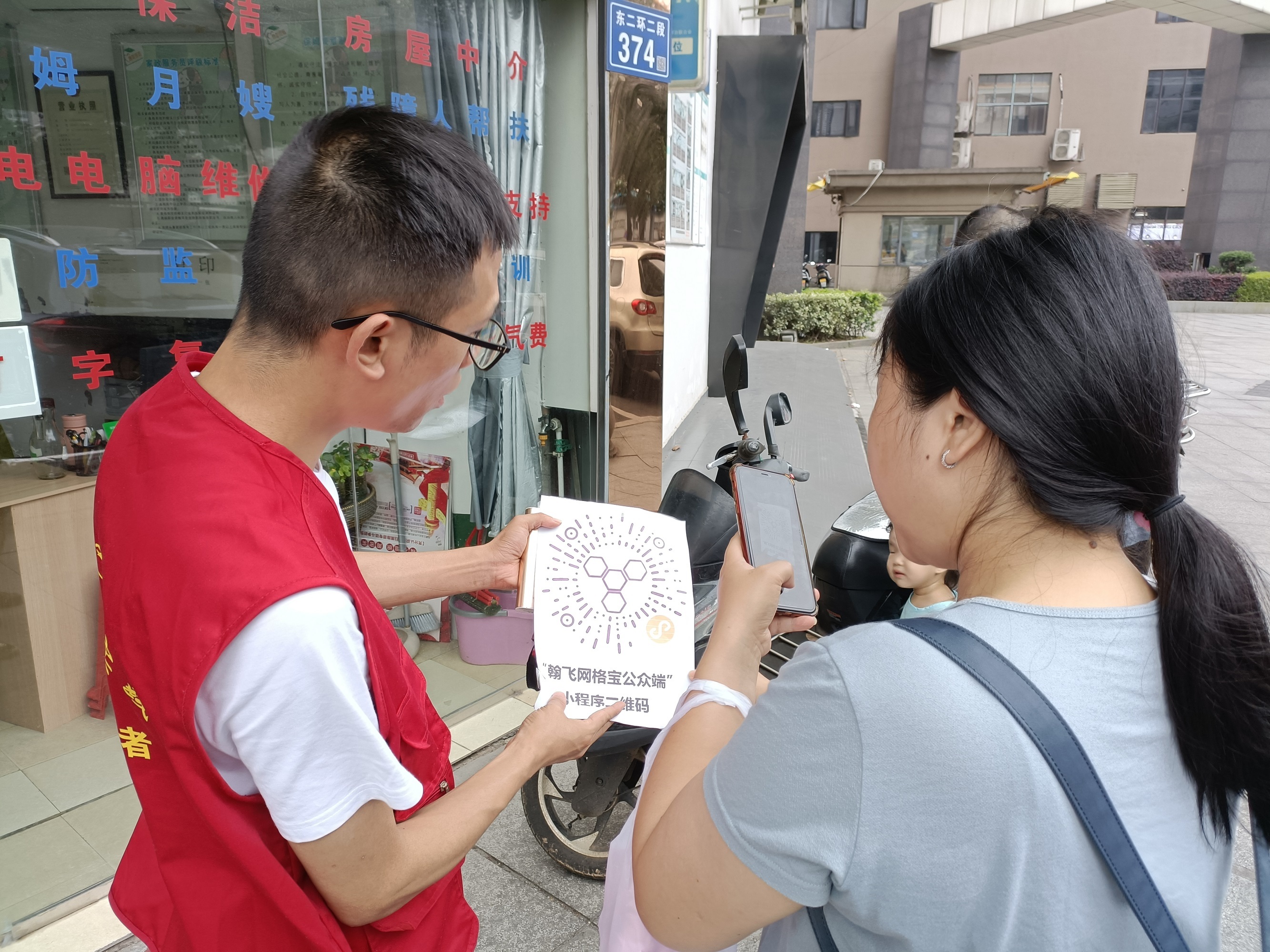 志愿者手拿“网格宝”的二维码向居民介绍“网格宝”的多种功能