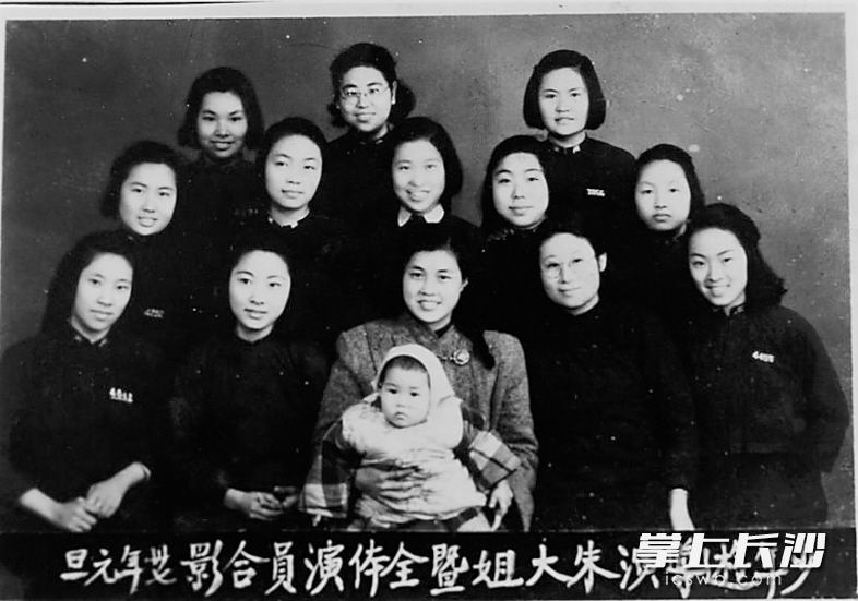 周南女校参加演出活动的演员和导演朱大姐的合影。朱大姐的大衣带着垫肩，挺括而大方；而第二排居中的女学生小立领父母装配上小衬衣领，显得清秀雅静。