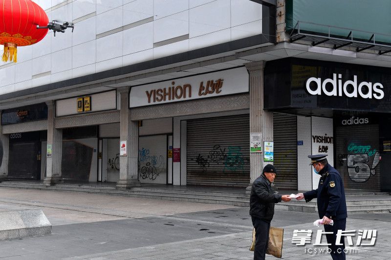 今日上午，黄兴南路步行街中心广场附近，城管队员给无人机发现的一名忘带口罩的市民送上口罩。