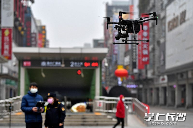 今日上午，黄兴南路步行街中心广场附近，两架无人机来回穿梭，向来往行人“花式”劝导戴口罩。 均为长沙晚报全媒体记者 王志伟 摄