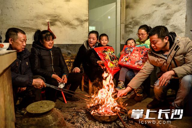 周奉章夫妻（左一、二）一家人和扶贫干部莫小代（左三）围坐在火堆边，谈收获谈打算。照片均为长沙晚报全媒体记者 陈飞 摄