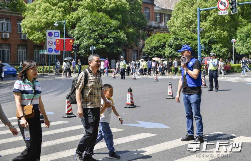 志愿者劝导游客有序通过马路。长沙晚报全媒体记者 余劭劼 摄 志愿者劝导游客有序通过马路。长沙晚报全媒体记者 余劭劼 摄