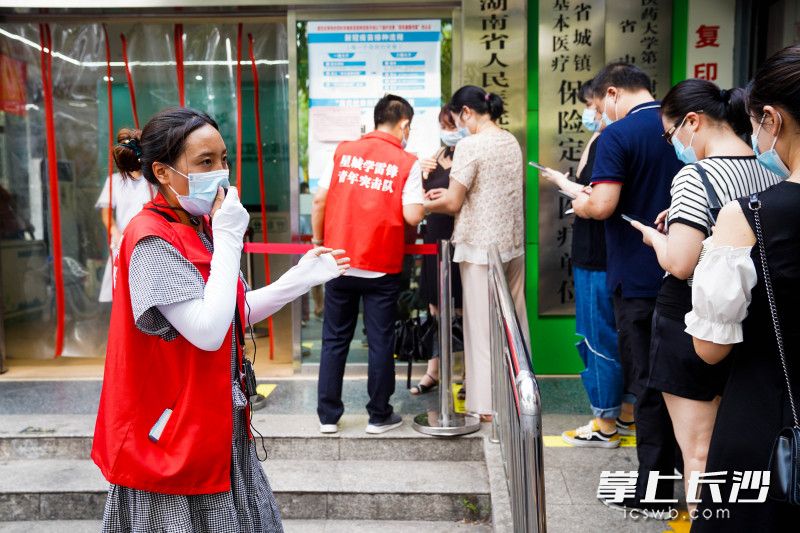8月3日下午，在荷花园街道社区卫生服务中心门前，星城学雷锋志愿者们正在劝导准备接受疫苗的市民有序排队。均为长沙晚报全媒体记者 周数邑 摄