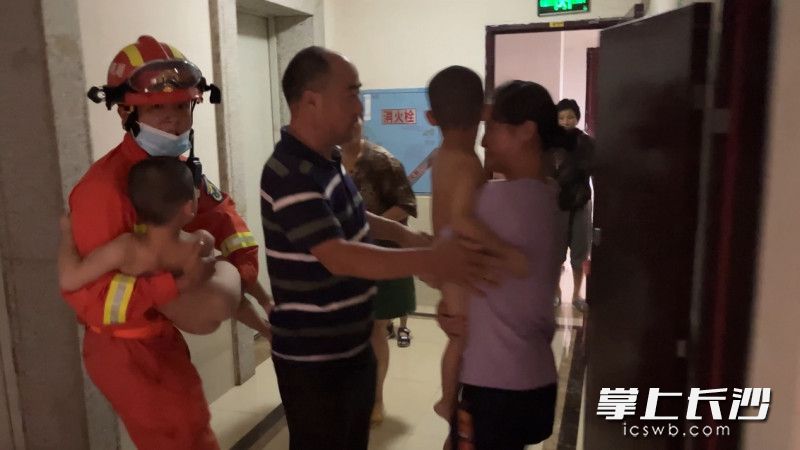 消防救援人员将两个孩子从火场中救出，交给家长。均为长沙晚报通讯员 张佳欣 供图