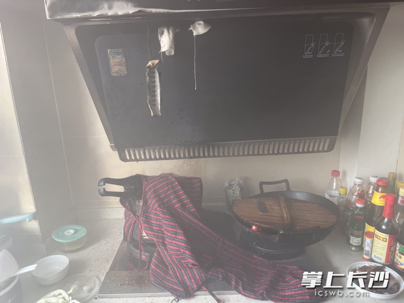 消防救援人员用棉布沾水后灭火，抽油烟机已被烧损。