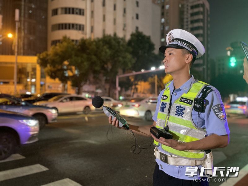 周文星正在用测量仪检测过往车辆的噪声分贝。