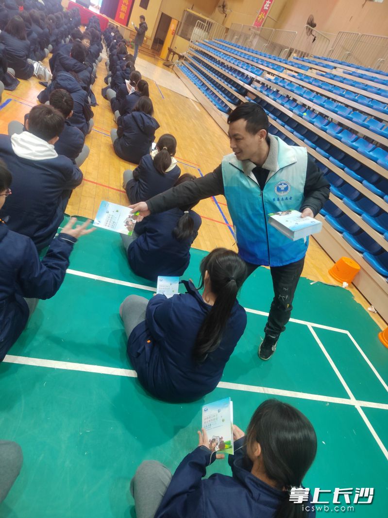 志愿者向学生发放毒品预防教育宣传手册。