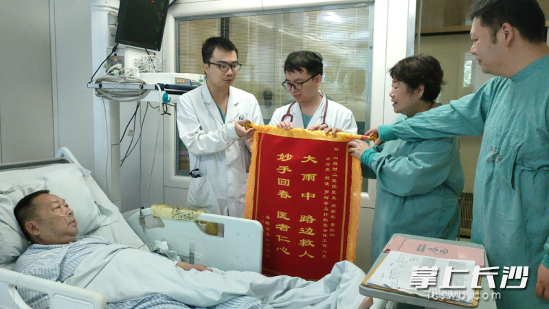 蔡大爷的老伴龚奶奶和儿子将锦旗交到医生手中。 长沙晚报全媒体记者 徐媛 实习生 谭仕兰 摄