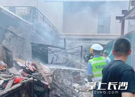 在确认安全的前提下，芙蓉交警熟练地拿起水枪，对准火源喷射，压制住火势。长沙晚报通讯员 屈省 供图