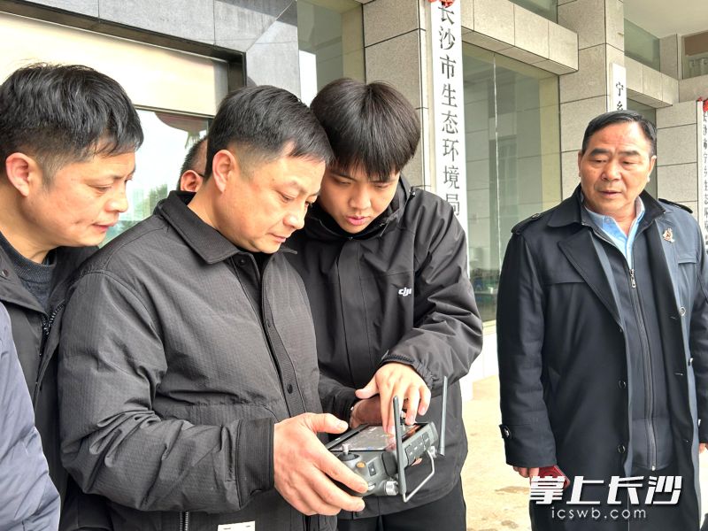 通过遥控器操控飞行，执法人员借助显示屏，可清晰查看远处企业的运行情况。