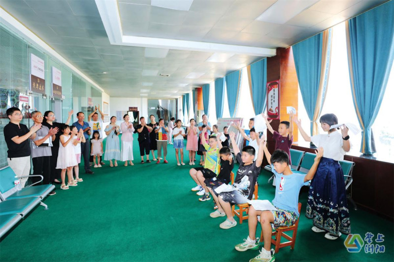 屋场内，孩子们正在排练节目，家长志愿者则在一旁指导。