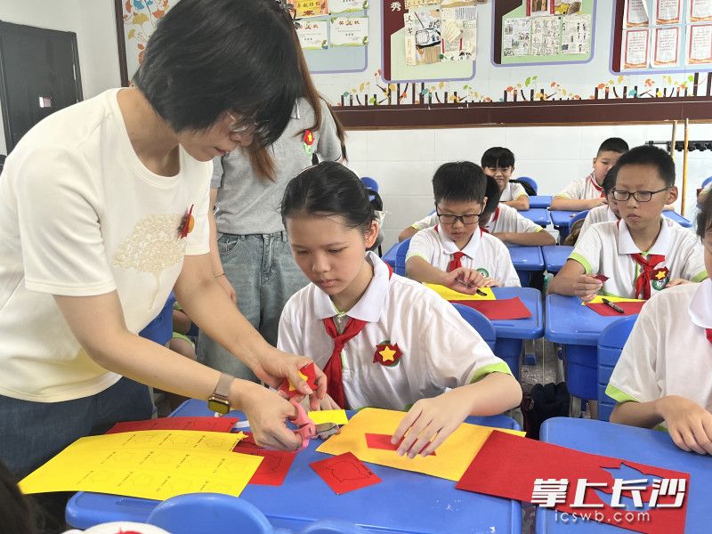在铜铺街小学，张丽走进少先队员中间，和他们一起制作胜利花。长沙晚报通讯员 贾微 摄