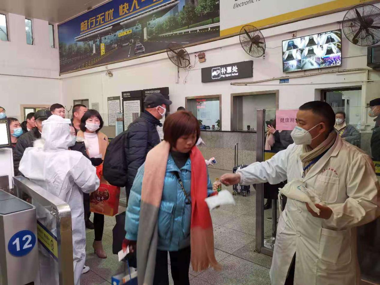 图为陈怡军在为火车站旅客发放口罩