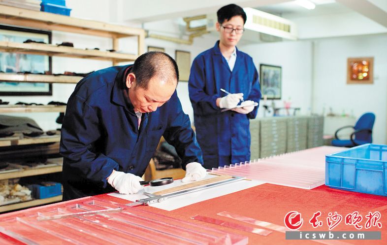 胡冬成（左）正在将一枚已经变形的木牍进行修复矫正。 长沙晚报全媒体记者 邹麟 董阳 摄影报道