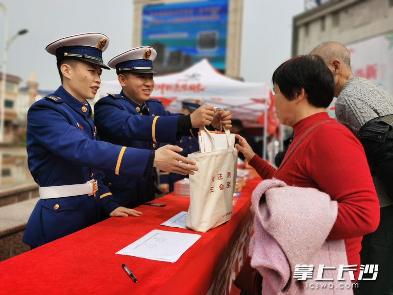 消防宣传员向群众发放消防宣传资料和小礼品。