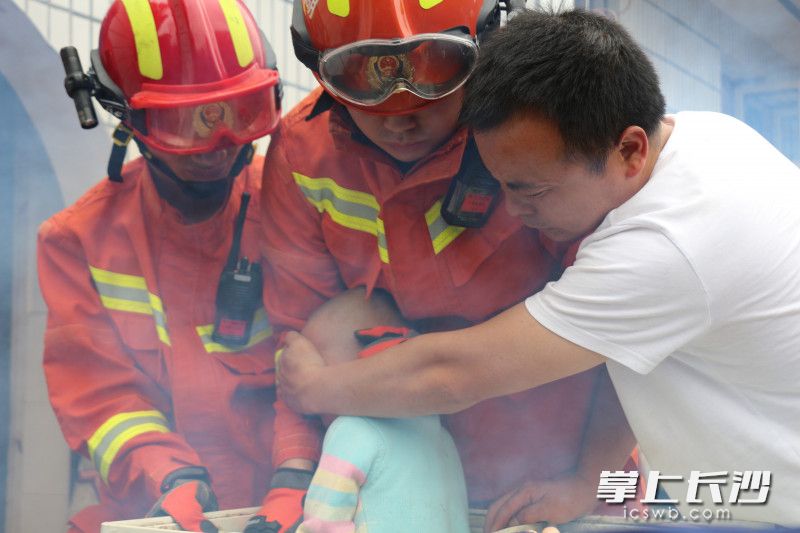 消防员进行破拆时，为安抚幼儿情绪，家长和消防员捂住其眼睛和耳朵。