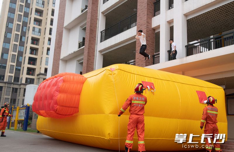 消防指战员第一时间打开消防救生气垫，指导“被困人员”安全跳落。