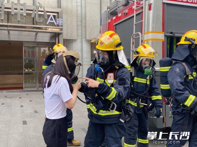 消防员为“被困人员”佩戴他救面罩并将其救出。