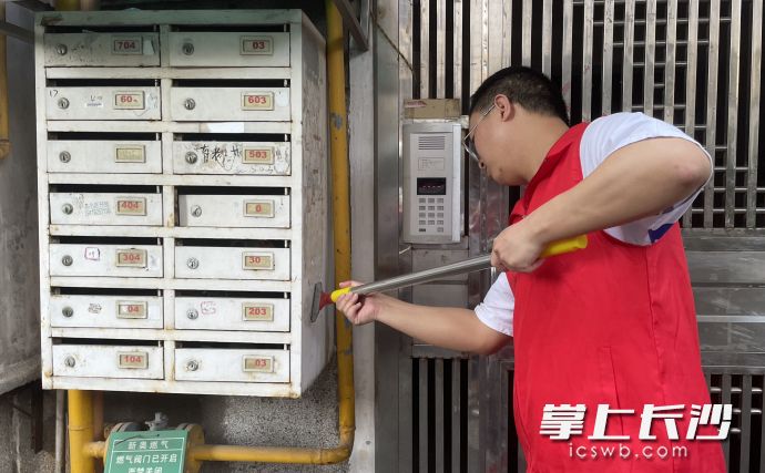 清水塘街道省公路局小区内，志愿者对“牛皮癣”进行清理。