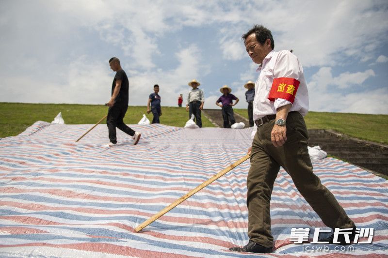 演练中，巡查人员在大坝外坡铺设彩条布防渗，并用沙袋压紧。