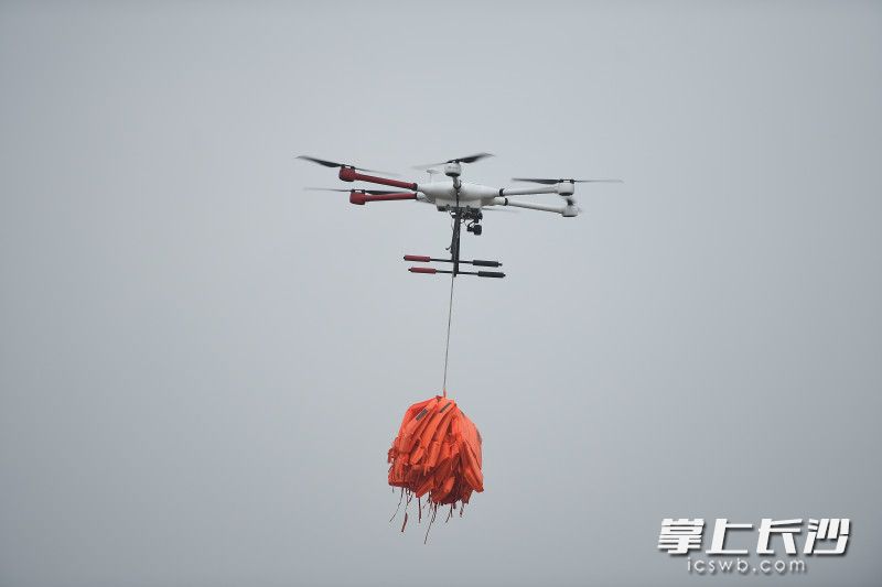 携带救生衣的无人机起飞，向岛上“被困群众”抛投救生衣。