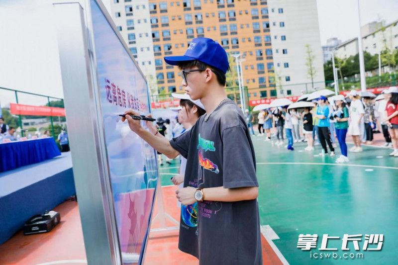 学生在“远离危房，从我做起”签名墙上签名。