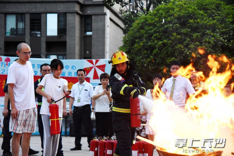 消防员示范使用干粉灭火器灭火。