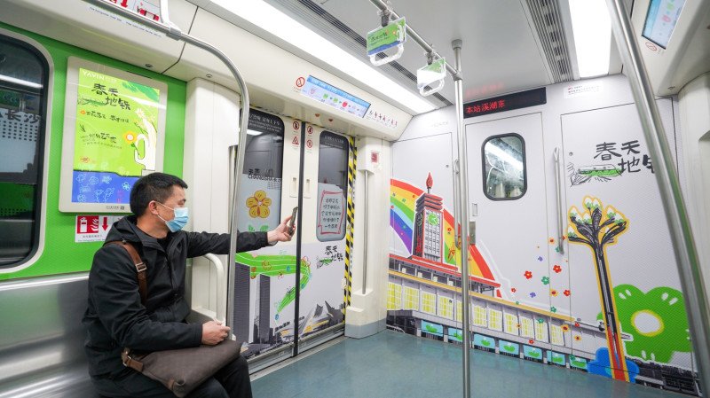 在长沙地铁2号线“春天地铁”专列上，乘客拿出手机打卡。均为亚文传媒 供图