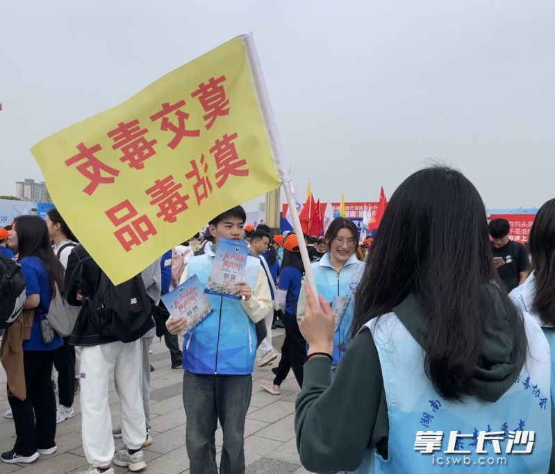 禁毒志愿者在出发点举着禁毒宣传小旗帜，发放禁毒宣传资料。 长沙晚报全媒体记者 聂映荣 摄