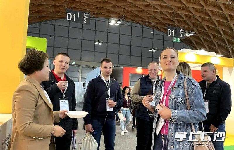 长沙穗宝农业科技有限公司的工作人员（左一）在展会向客商推存品尝无花果干。受访者 供图