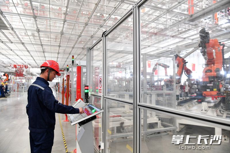 三一商用车智造公司冲焊工作中心班组长陈鑫与他的机器人“工友”焊接机器人，正在进行协同作业。长沙晚报全媒体记者 王志伟摄