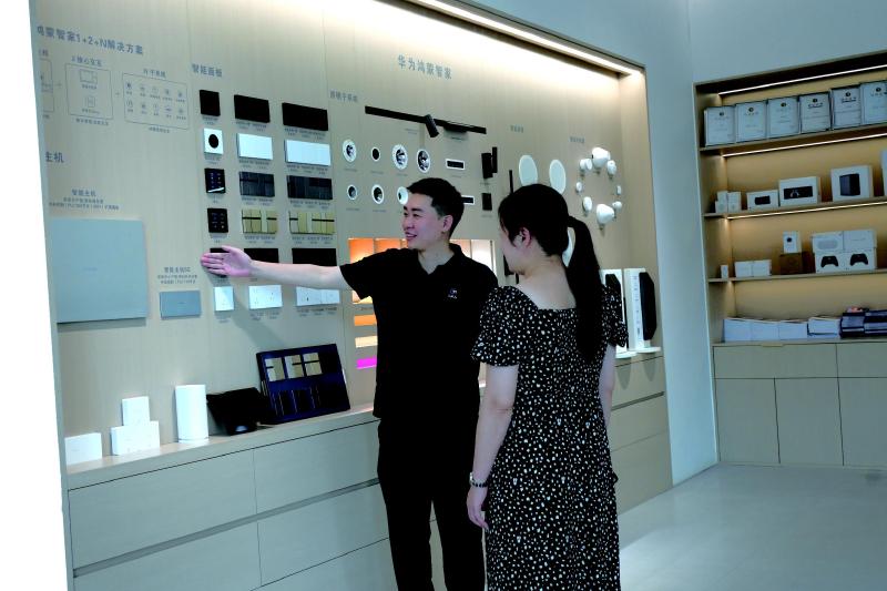 李昌津（左）为顾客介绍展厅里的智能面板。