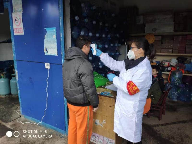 图为村医正在为村民检测体温