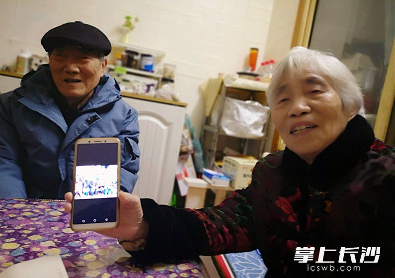 老伴李锦霞向记者展示存在手机里的一大家人曾留下的幸福合影。长沙晚报全媒体记者 周和平 摄
