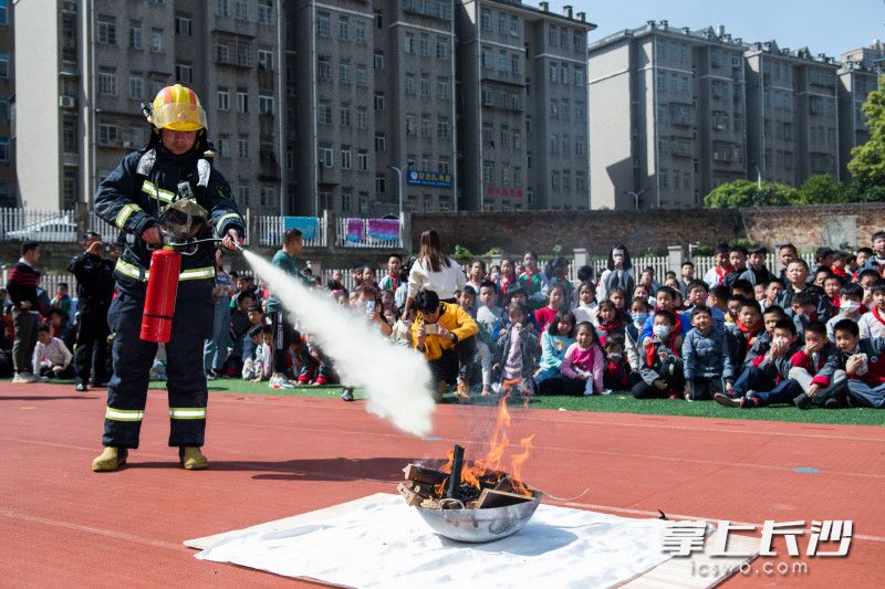 消防员现场演示干粉灭火器的使用方法。