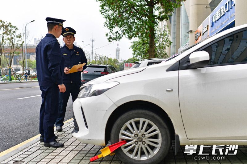 在锦泰广场，芙蓉区行政执法大队城管执法人员对人行道违停车辆进行处罚。