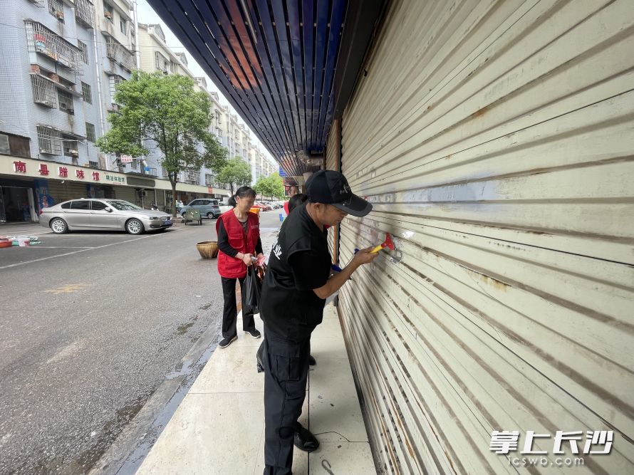 物业、居民志愿者动手铲除“牛皮癣”。