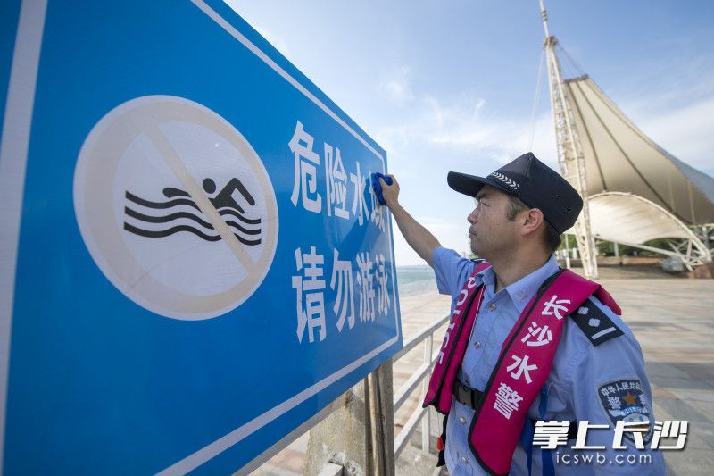 郑苗对岸边竖立的安全警示牌进行检查和维护。