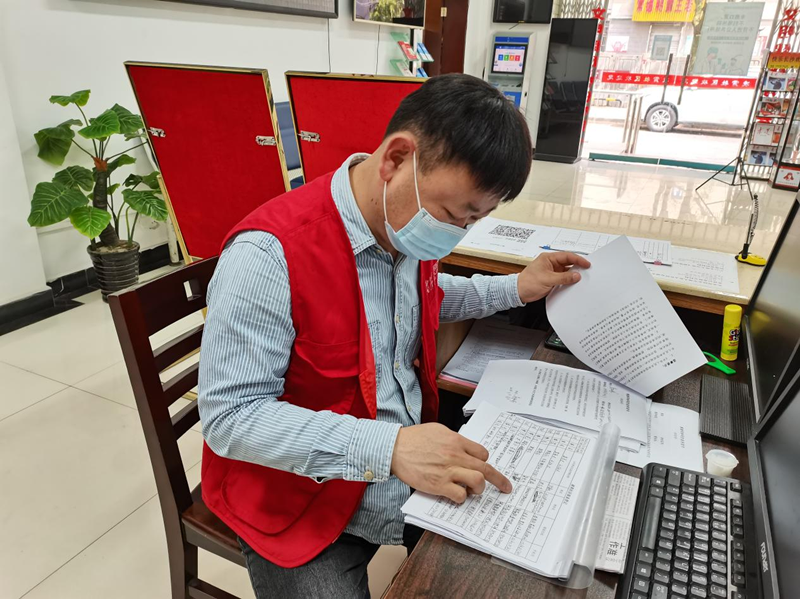 志愿者江多利正协助社区工作人员做好居民报备转码工作。