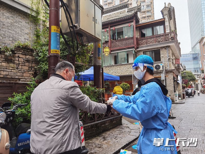 不少爱心商户的员工主动当起了志愿者，配合社区维护防疫秩序。 全媒体记者 周游 摄