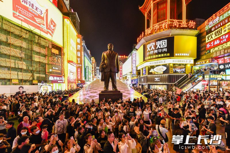 5月1日，长沙黄兴南路步行街游客们在大屏幕前拍照留念。