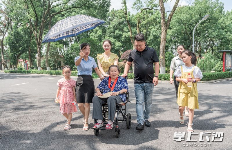 爱心志愿者陪着百岁抗战女兵散步拉家常。