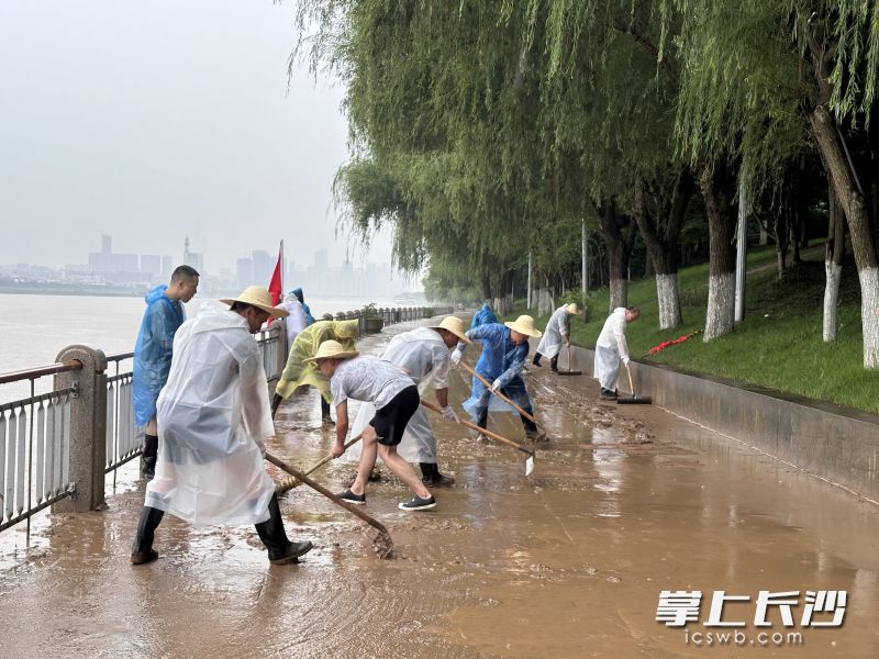清淤工作人员头戴草帽、身着雨衣、脚穿雨靴冒雨奋战。