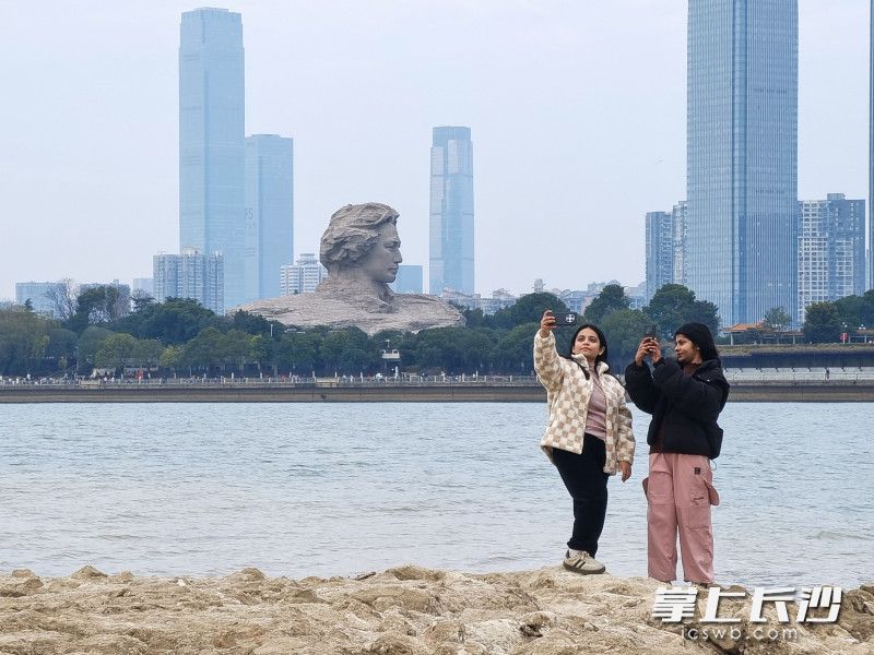 尼泊尔留学生阿妮塔与同伴在江滩公园与青年毛泽东艺术雕塑合影留念。