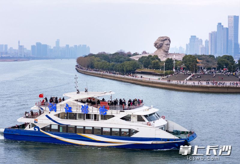 市民游客在湘江游轮上拍摄青年毛泽东艺术雕塑。