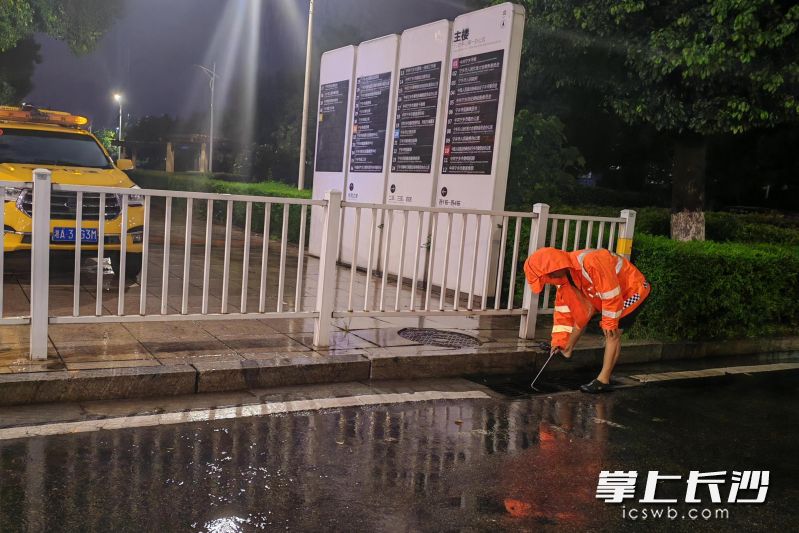 宁乡市住建局城区排水中心值守人员在打开井盖加速排水。