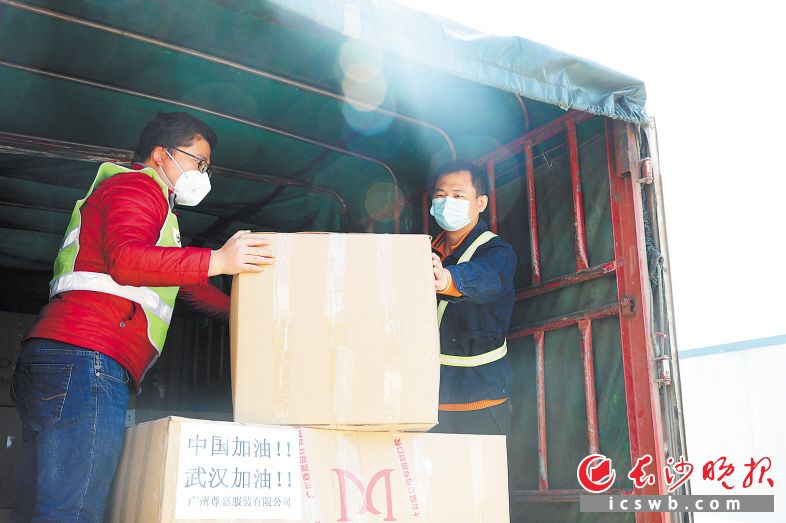 接受采访时，郑李辉（右）正在帮助同事装运羽绒服、辣酱等生活物资以驰援湖南支援湖北医疗队。长沙晚报通讯员 黄姿 摄