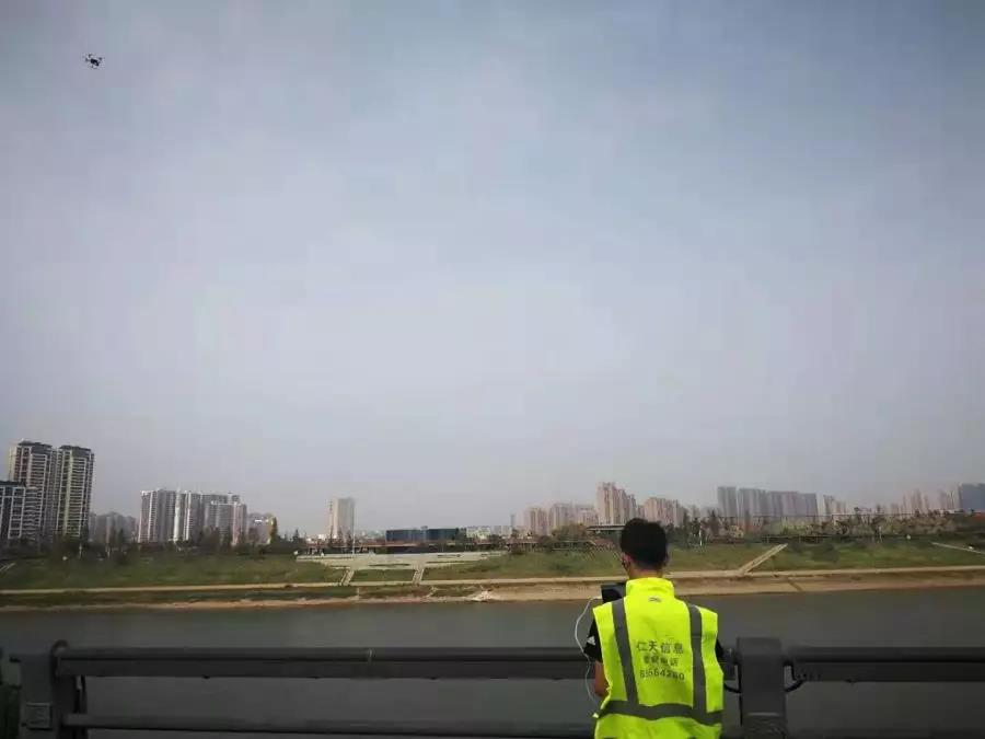 信息采集员正在操作无人机飞跃浏阳河，对河岸垃圾清理情况进行采集