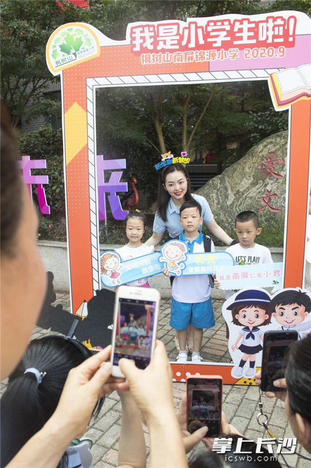 一年级新生和老师在“我是小学生啦”成长框前合影。