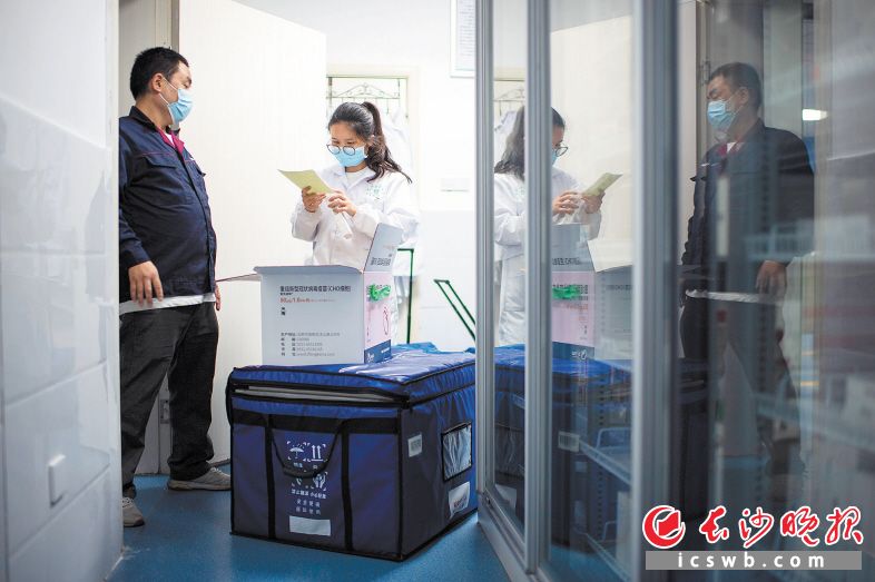 27日 21:17 在天顶街道社区卫生服务中心冷链室,郭国顺与工作人员交接疫苗。 27日 21:17 在天顶街道社区卫生服务中心冷链室,郭国顺与工作人员交接疫苗。